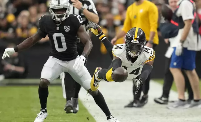 Pittsburgh Steelers wide receiver George Pickens (14) dives forward after catching a pass in front of Las Vegas Raiders cornerback Jakorian Bennett (0) during the first half of an NFL football game in Las Vegas, Sunday, Oct. 13, 2024. (AP Photo/John Locher)