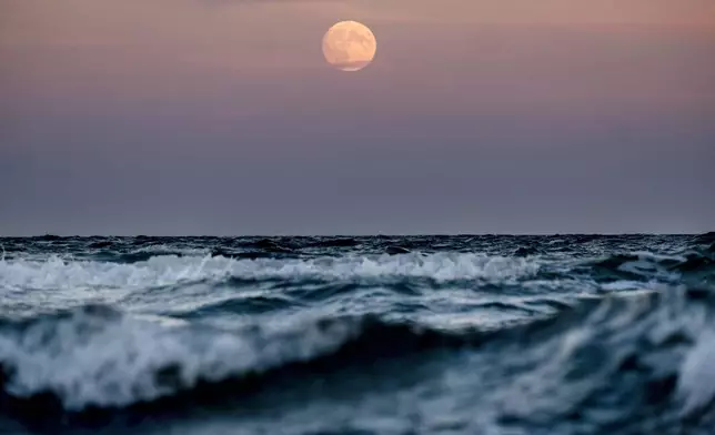 The moon rises over the Baltic Sea in Haffkrug, northern Germany, Wednesday, Oct. 16, 2024. (AP Photo/Michael Probst)