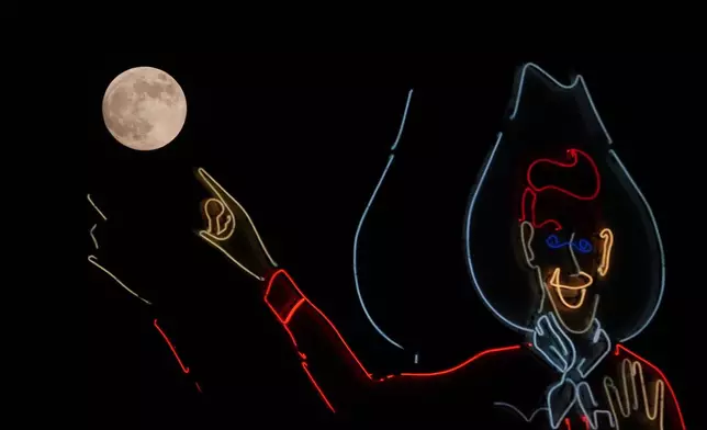 The moon rises next to a neon Big Tex at the State Fair of Texas in Dallas, Wednesday, Oct. 16, 2024. (AP Photo/LM Otero)