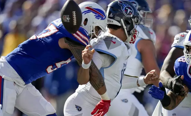 Buffalo Bills defensive end AJ Epenesa (57) strips the ball from Tennessee Titans quarterback Mason Rudolph, right, during the first half of an NFL football game Sunday, Oct. 20, 2024, in Orchard Park, N.Y. (AP Photo/Charles Krupa)