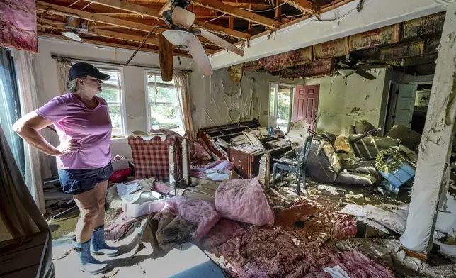 Cindy White looks over the devastation inside her home caused by Hurricane Helene, Tuesday, Oct. 1, 2024 in Morganton, N.C. The adjacent Catawba River flooded due to the torrential rains destroying the seven of family's nine homes on the property. (AP Photo/Kathy Kmonicek)