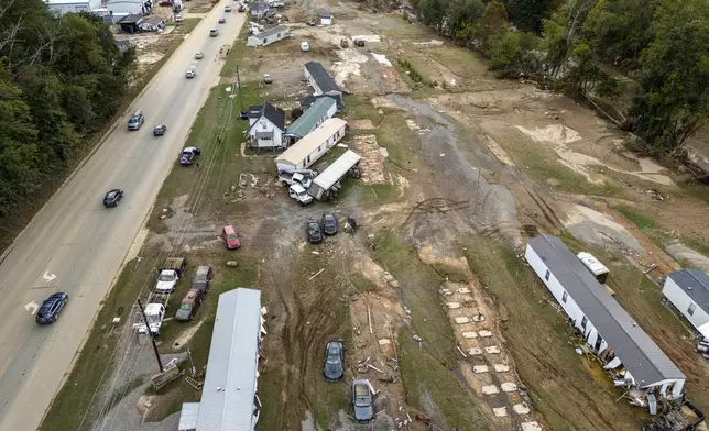 Homes and vehicles that were damaged in a flash flood from Hurricane Helene lie on the side of a road near the Swannanoa River, Tuesday, Oct. 1, 2024, in Swannanoa, N.C. (AP Photo/Mike Stewart)