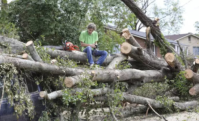 Andy Brown takes a break on top of what remains of a tree that destroyed his SUV when it fell during Hurricane Helene on in Augusta, Ga., Tuesday, Oct. 1, 2024. (AP Photo/Jeffrey Collins)