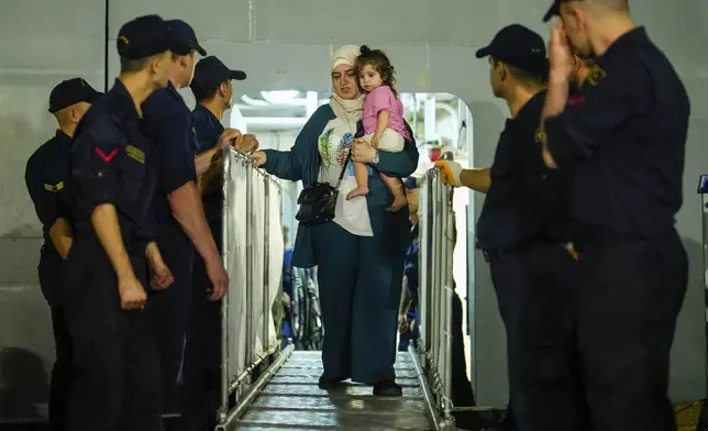 People, mostly Turkish nationals, disembark from Turkish TCG Sancaktar military ship after being evacuated from Lebanon's capital Beirut to Turkey, in Mersin port, southern Turkey, early Friday, Oct. 11, 2024. (AP Photo/Emrah Gurel)