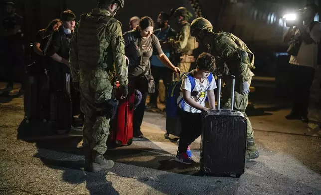 Turkish citizens walk to board Turkish military ships evacuating them from Lebanon to Turkey, in Beirut port on Wednesday, Oct. 9, 2024. (AP Photo/Emrah Gurel)