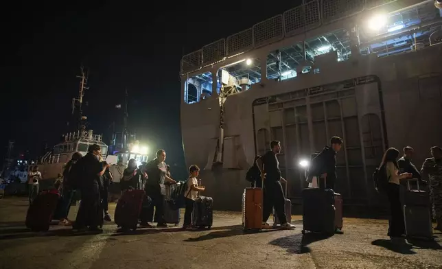 Turkish citizens walk to board Turkish military ships evacuating them from Lebanon to Turkey, in Beirut port on Wednesday, Oct. 9, 2024. (AP Photo/Emrah Gurel)