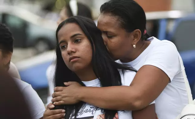 A relative hugs Saray Barrios — whose husband, brother and brother in-law were arrested in a crackdown after protests against the election results — during a manifestation outside Tocuyito prison in Carabobo state, Venezuela, Wednesday, Oct. 16, 2024. (AP Photo/Jacinto Oliveros)