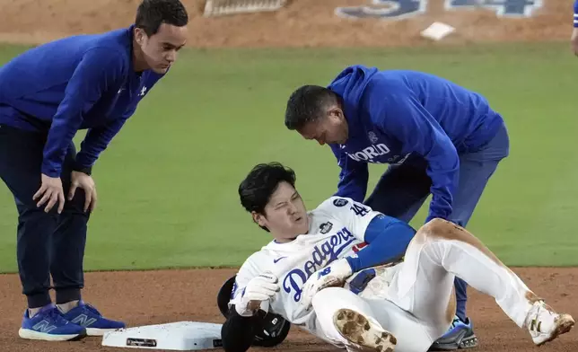 Los Angeles Dodgers' Shohei Ohtani, center, reacts after being injured while trying to steal second base against the New York Yankees during the seventh inning in Game 2 of the baseball World Series, Saturday, Oct. 26, 2024, in Los Angeles. (AP Photo/Julio Cortez)