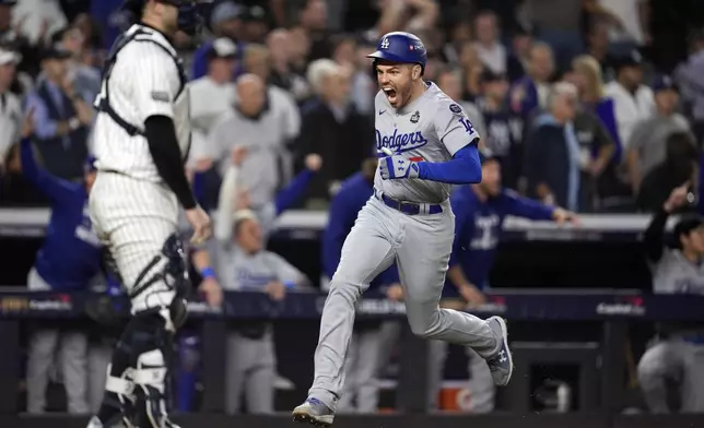 Los Angeles Dodgers' Freddie Freeman, right, runs toward home plate to score against the New York Yankees during the fifth inning in Game 5 of the baseball World Series, Wednesday, Oct. 30, 2024, in New York. (AP Photo/Godofredo A. Vásquez)