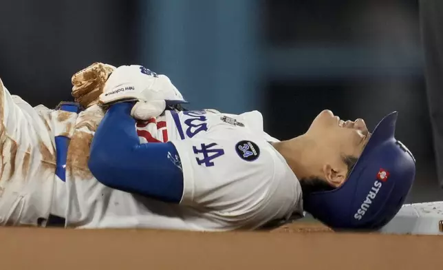 Los Angeles Dodgers' Shohei Ohtani holds his arm after being injured while attempting to steal second base during the seventh inning in Game 2 of the baseball World Series against the New York Yankees, Saturday, Oct. 26, 2024, in Los Angeles. (AP Photo/Ashley Landis)