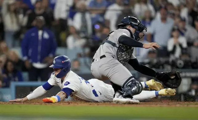 Los Angeles Dodgers' Kiké Hernández scores past New York Yankees catcher Austin Wells on a sacrifice fly by Will Smith during the fifth inning in Game 1 of the baseball World Series, Friday, Oct. 25, 2024, in Los Angeles. (AP Photo/Ashley Landis)