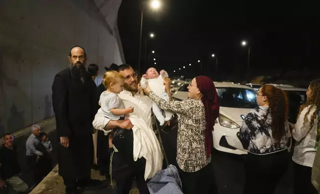 People take cover on the side of the road as a siren sounds a warning of incoming missiles fired from Iran on a freeway in Shoresh, between Jerusalem and Tel Aviv in Israel Tuesday, Oct. 1, 2024. (AP Photo/Ohad Zwigenberg)