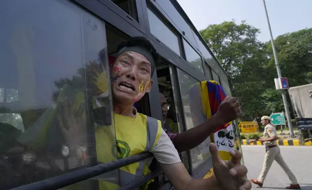 An exile Tibetan shouts slogans against the human rights situation in Tibet from a police vehicle as he is detained during a protest to coincide China marking its 75th year of Communist Party rule, outside Chinese embassy, in New Delhi, India, Tuesday, Oct. 1, 2024. (AP Photo/Manish Swarup)