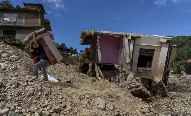 A man recovers his furniture from a damaged house on the bank of Nallu river, in the aftermath of a flood caused by heavy rains, in Lalitpur, Nepal, Tuesday, Oct. 1, 2024. (AP Photo/Niranjan Shrestha)