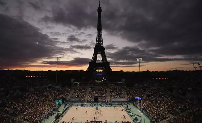 FILE - The Eiffel Tower looms in the background during play in the women's beach volleyball bronze medal match between Australia, left, and Switzerland, right, at the 2024 Summer Olympics, Aug. 9, 2024, in Paris, France. (AP Photo/Louise Delmotte, File)