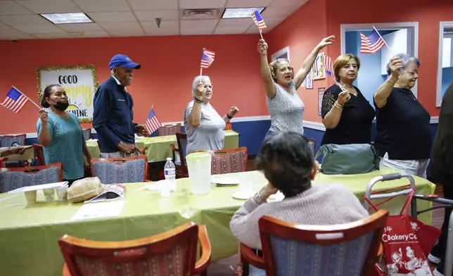 People march in a line as they take part in a multicultural parade at Sunshine Adult Day Center in Bergenfield, N.J., Monday, Aug. 26, 2024. (AP Photo/Kena Betancur)