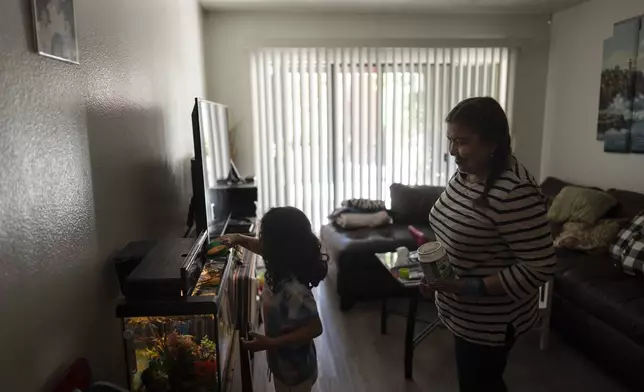 Marina Maalouf, a longtime resident of Hillside Villa, watches as her granddaughter feeds fish in their apartment in Los Angeles, Tuesday, Oct. 1, 2024. (AP Photo/Jae C. Hong)