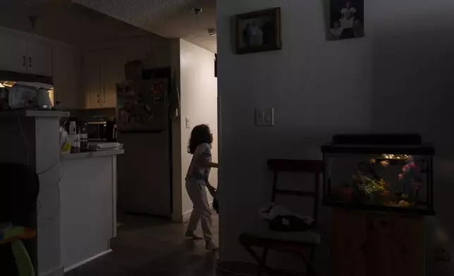 Rubie Caceres, a granddaughter of Marina Maalouf, a longtime resident of Hillside Villa who participated in protests after rents doubled in 2019, enters a bedroom in her apartment in Los Angeles, Tuesday, Oct. 1, 2024. (AP Photo/Jae C. Hong)