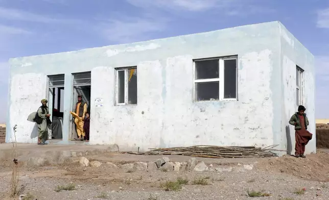 Survivors are stand in front of their new house is seen in Zinda Jan district, of Herat province, in western Afghanistan, Saturday, Sept. 28, 2024 following a 6.3 magnitude earthquake on Oct. 7, 2023. (AP Photo/Omid Haqjoo)