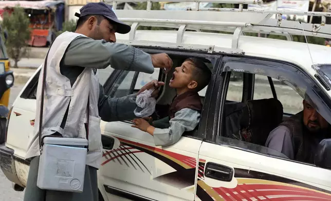 A health worker administers a polio vaccine to a child inside a Taxi in the city of Jalalabad, east of Kabul, Afghanistan, Tuesday, Oct. 29, 2024. (AP Photo/Shafiullah Kakar)