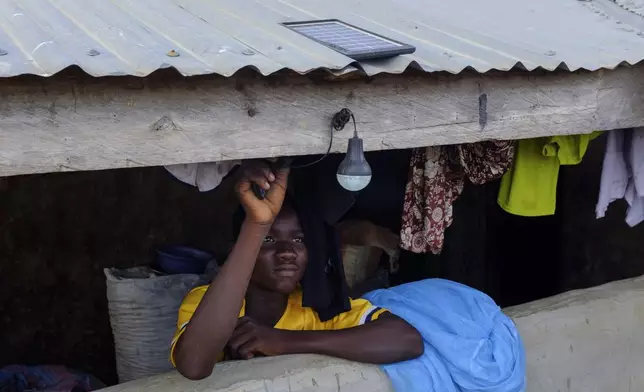 Yahya Alhassan tests a light bulb with a solar system at his home in Gushegu northern, Ghana, Friday Sept 6, 2024. (AP Photos/Abdul Haqq Mahama)