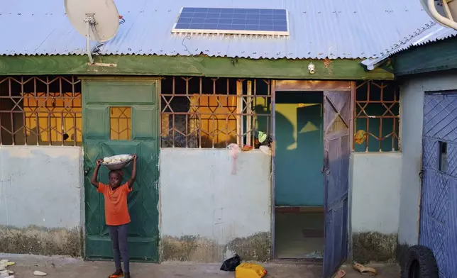 A girl stands in front of a house connected to solar system in Gushegu northern, Ghana, Friday Sept. 6, 2024. (AP Photos/Abdul Haqq Mahama)