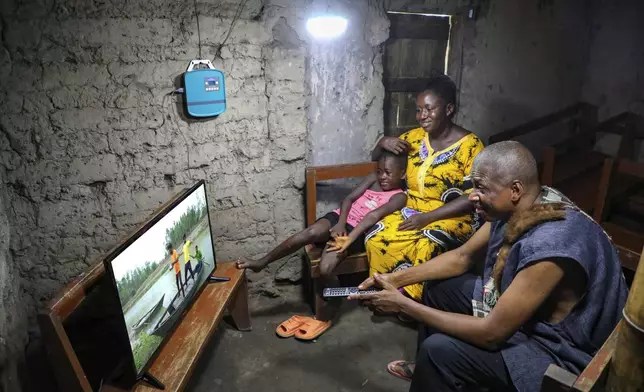 This photo released by Easy Solar shows a man and his family watching television with a solar power in his house in Monrovia, Liberia, Saturday Aug. 26, 2023. (Muctarr Bah Mohamed/Easy Solar via AP)