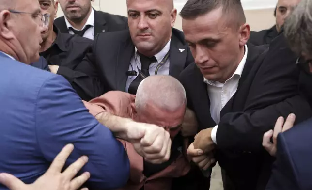 Albanian Parliament's security move away Ramadan Lika, center, lawmaker of conservative opposition Democratic Party, as he tried to disrupt the parliament's session during a protest for the imprisonment of a fellow lawmaker in Tirana, Albania, Thursday, Oct. 3, 2024. (AP Photo/Hameraldi Agolli)