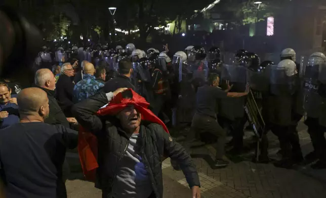 Opposition supporters scuffle with riot police during a anti-government rally, in Tirana, Albania, Monday, Oct. 7, 2024. (AP Photo/Hameraldi Agolli)