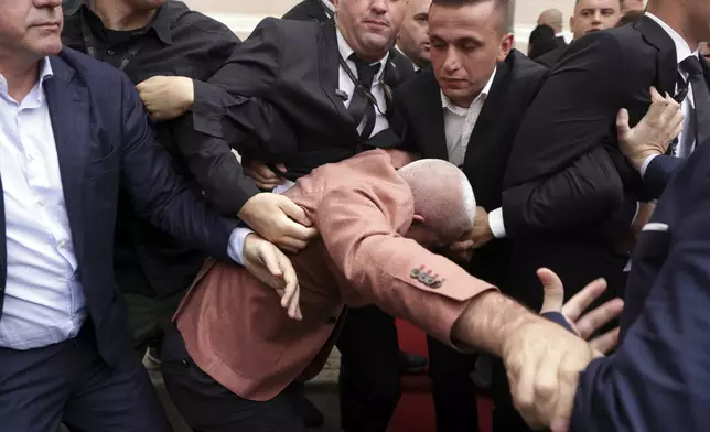 Albanian Parliament's security move away Ramadan Lika, center, lawmaker of conservative opposition Democratic Party, as he tried to disrupt the parliament's session during a protest for the imprisonment of a fellow lawmaker in Tirana, Albania, Thursday, Oct. 3, 2024. (AP Photo/Hameraldi Agolli)