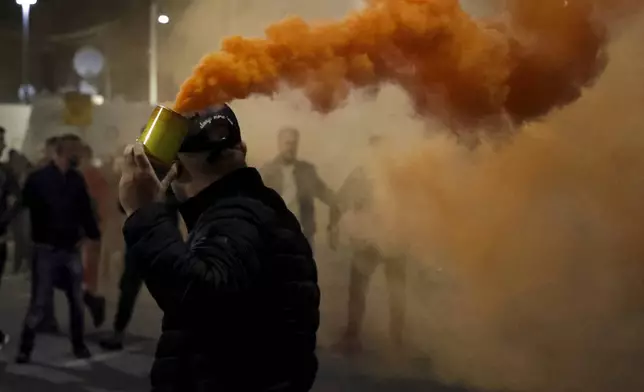 An opposition protester holds a flare during an anti-government rally set up by the opposition, in Tirana, Albania, Monday, Oct. 7, 2024. (AP Photo/Hameraldi Agolli)