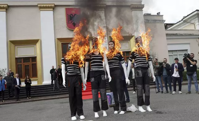 Albanian opposition lawmakers put fire on mannequins depicting members of the Socialist Party government during a protest for the imprisonment of a fellow lawmaker in Tirana, Albania, Thursday, Oct. 3, 2024. (AP Photo/Hameraldi Agolli)