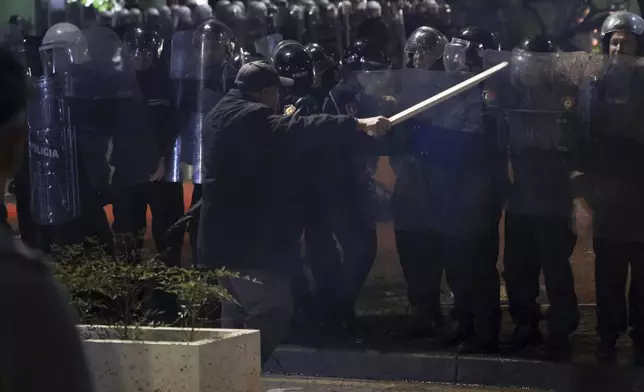 An opposition supporter waves a wooden stick to riot police during a anti-government rally, in Tirana, Albania, Monday, Oct. 7, 2024. (AP Photo/Hameraldi Agolli)