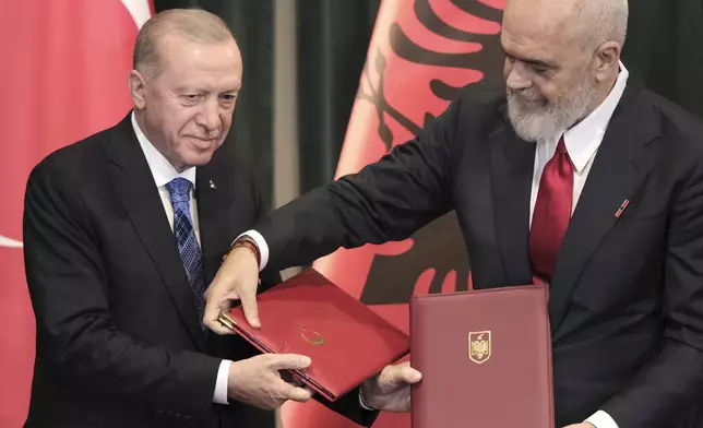 Prime Minister of Albania Edi Rama, right, exchange envelops with Turkey's President Recep Tayyip Erdogan after they sing bilateral agreements in Tirana, Albania, Thursday, Oct. 10, 2024. (AP Photo/Vlasov Sulaj)