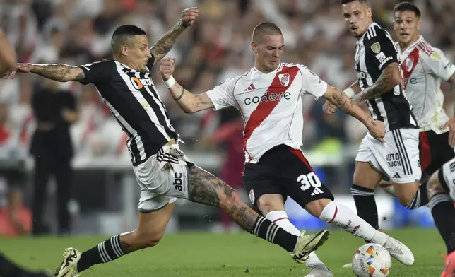 Franco Mastantuono of Argentina's River Plate, center, and Junior Alonso of Brazil's Atletico Mineiro battle for the ball during a Copa Libertadores semifinal second leg soccer match at Monumental stadium in Buenos Aires, Argentina, Tuesday, Oct. 29, 2024. (AP Photo/Gustavo Garello)
