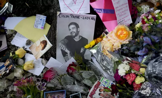 A picture of former One Direction singer Liam Payne sits surrounded by flowers and candles as fans gather outside the hotel where he was found dead after falling from a balcony in Buenos Aires, Argentina, Thursday, Oct. 17, 2024. (AP Photo/Natacha Pisarenko)