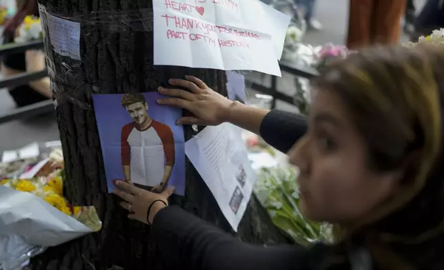 A fan of former One Direction singer Liam places a photo of him on a tree outside the hotel where he was found dead after falling from a balcony the previous day in Buenos Aires, Argentina, Thursday, Oct. 17, 2024. (AP Photo/Natacha Pisarenko)