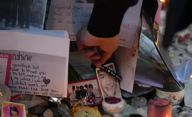 Geoff Payne, the father of former One Direction singer Liam Payne, touches a gel bracelet hanging on a picture of his son while visiting a memorial outside the Casa Sur Hotel where the British pop singer fell to his death from a hotel balcony, in Buenos Aires, Argentina, Friday, Oct. 18, 2024. (AP Photo/Natacha Pisarenko)