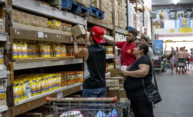 People buy groceries at a supermarket that accepts "chachos" currency in La Rioja, Argentina, Monday, Sept. 23, 2024. In response to slashed federal budgets to provinces, La Rioja is printing a new emergency tender called "chachos" to pay state workers and spur the economy. (AP Photo/Natalia Diaz)