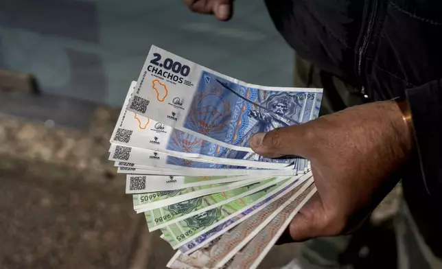 A vendor holds "chacho" currency at the Exchange Service Center to convert them to Argentine pesos in La Rioja, Argentina, Friday, Sept. 13, 2024. La Rioja province is printing this new emergency tender to pay state workers and spur the economy after the government slashed federal budgets to provinces. (AP Photo/Natalia Diaz)