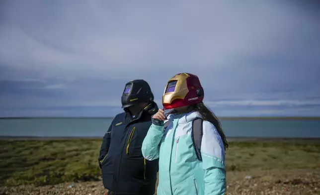 Sebastian Caceres and Guadalupe Caceres, right, watch an annular solar eclipse in Puerto San Julian, Argentina, Wednesday, Oct. 2, 2024. (AP Photo/Natacha Pisarenko)