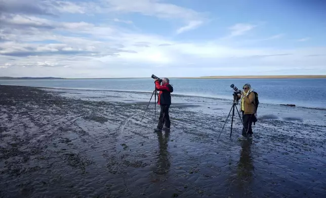 People photograph an annular solar eclipse in Puerto San Julian, Argentina, Wednesday, Oct. 2, 2024. (AP Photo/Natacha Pisarenko)