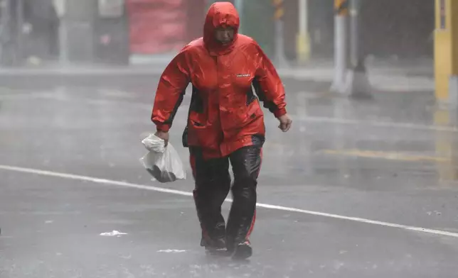 A woman struggles in the wind and rain generated by Typhoon Krathon in Kaohsiung, southern Taiwan, Thursday, Oct. 3, 2024. (AP Photo/Chiang Ying-ying)