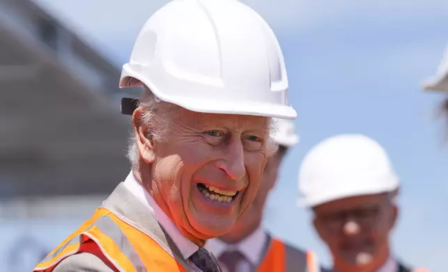 Britain's King Charles III wears a protective hat as he visits the Homes NSW Cowper Street development in Sydney, Australia, Tuesday, Oct. 22, 2024. (AP Photo/Mark Baker, Pool)