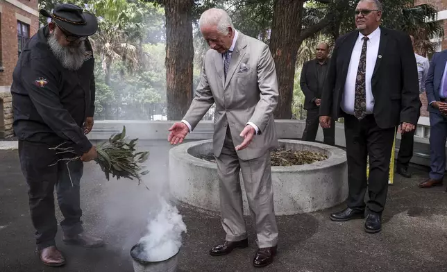 King Charles III, center, participates in a traditional smoking ceremony conducted by community representatives from the Gadigal people of the Eora Nation during a visit to the National Centre of Indigenous Excellence on Tuesday Oct. 22, 2024 in Sydney, Australia. (Lisa Maree Williams/Pool Photo via AP)