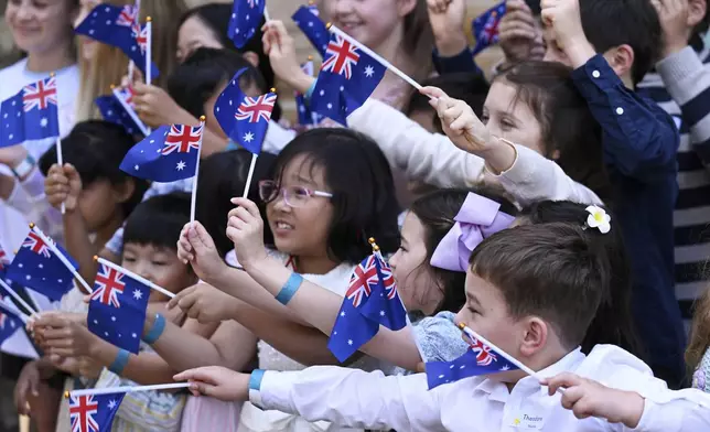 Children wave New Zealand flags as King Charles III and Queen Camilla visit St Thomas' Anglican Church in Sydney, Sunday, Oct. 20, 2024. (Dean Lewins/Pool Photo via AP)