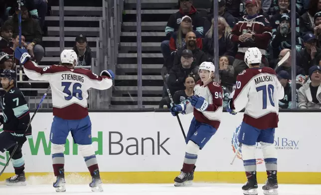 Colorado Avalanche left wing Joel Kiviranta, center, reacts to his first goal along with center Matt Stienburg, left, and defenseman Sam Malinski, right, against the Seattle Kraken during the first period of an NHL hockey game, Tuesday, Oct. 22, 2024, in Seattle. The Avalanche won 3-2. (AP Photo/John Froschauer)