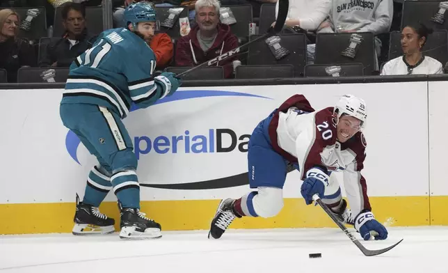 San Jose Sharks center Luke Kunin, left, and Colorado Avalanche center Ross Colton (20) fight for the puck during the first period of an NHL hockey game in San Jose, Calif., Sunday, Oct. 20, 2024. (AP Photo/Minh Connors)