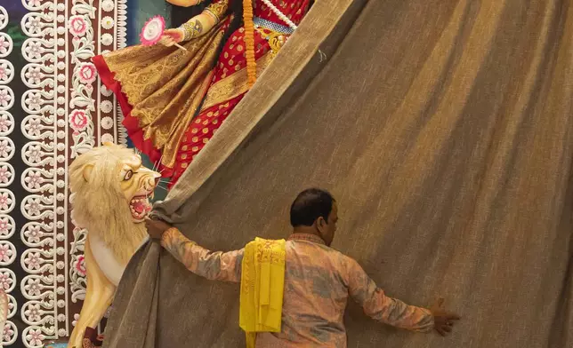 A priest opens the curtain of a tableau depicting an idol of Hindu goddess Durga at Dhakeshwari National Temple during the Durgapuja festival in Dhaka, Bangladesh, on Oct. 10, 2024. (AP Photo/Rajib Dhar)