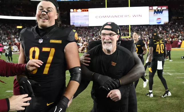 Washington Commanders head coach Dan Quinn and tight end John Bates (87) celebrate after the Commanders beat the Chicago Bears 18-15 in an NFL football game Sunday, Oct. 27, 2024, in Landover, Md. (AP Photo/Nick Wass)